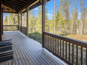 Une terrasse en bois dotée d’une rambarde, qui offre une vue sur une zone boisée.