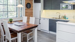 Een moderne keuken met witte kastjes, een houten eettafel en een klok aan de muur.