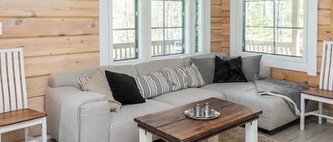 A cozy cabin interior with a sectional sofa, a coffee table, and two white chairs.