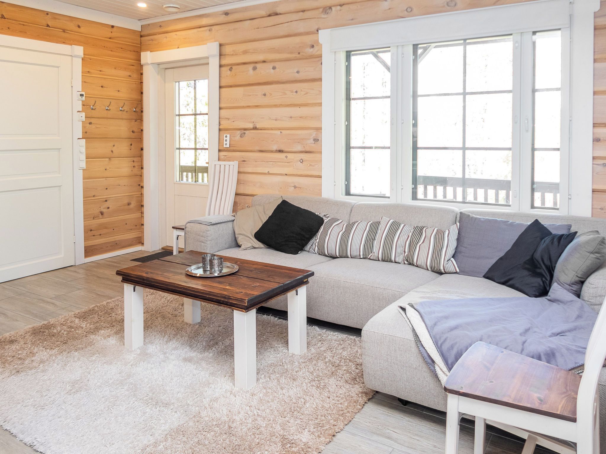 A cozy room with a wooden interior, a sofa, a coffee table, and a window with a view.