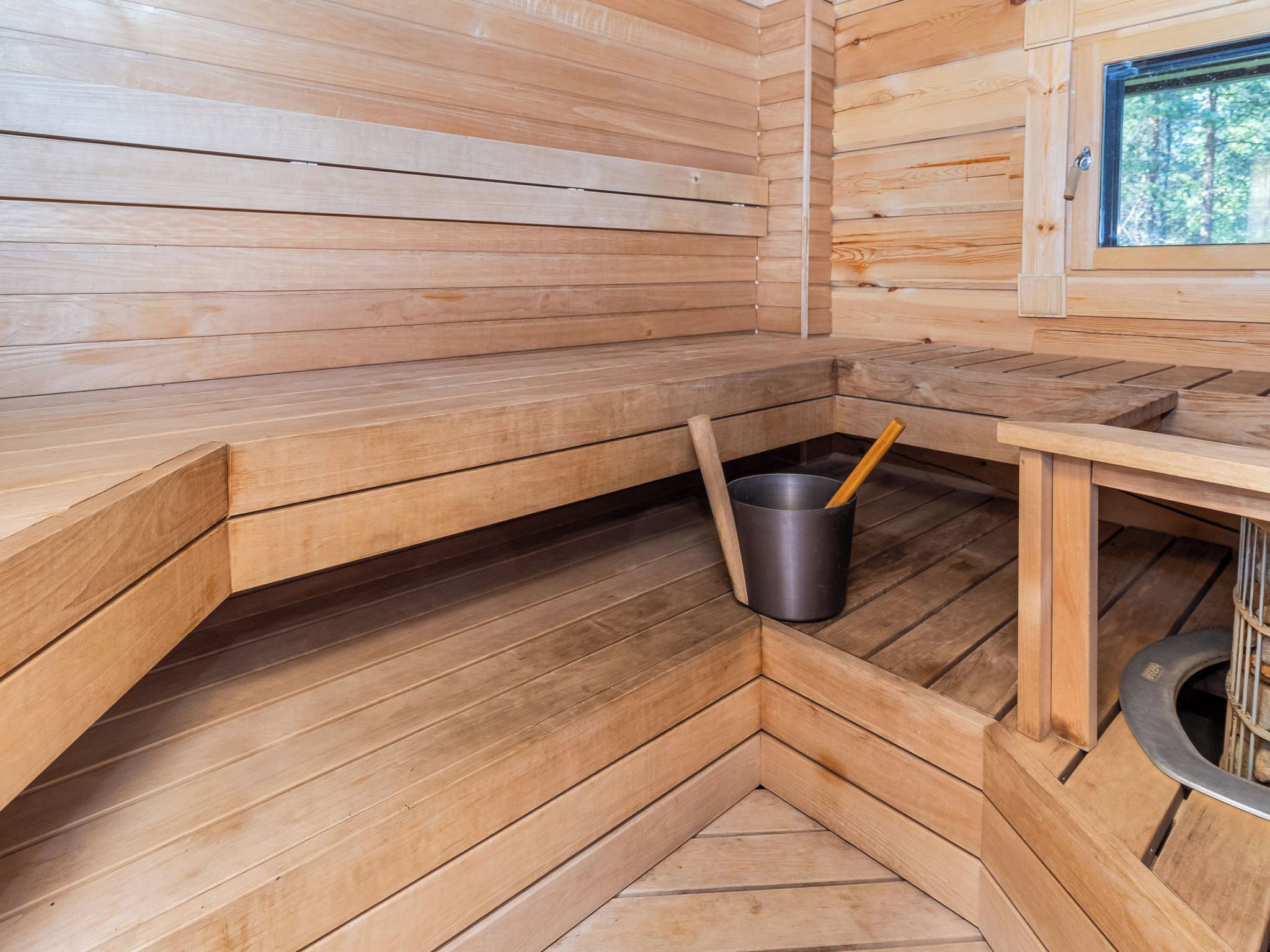 Una sala de sauna con bancos de madera y un cubo de metal.