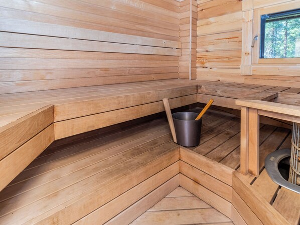 Un sauna avec des bancs en bois et un seau en métal.