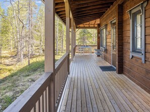 Une cabane en bois avec une véranda couverte, une table et des chaises.