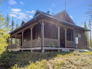Une cabane en bois avec un porche, entourée d’arbres.