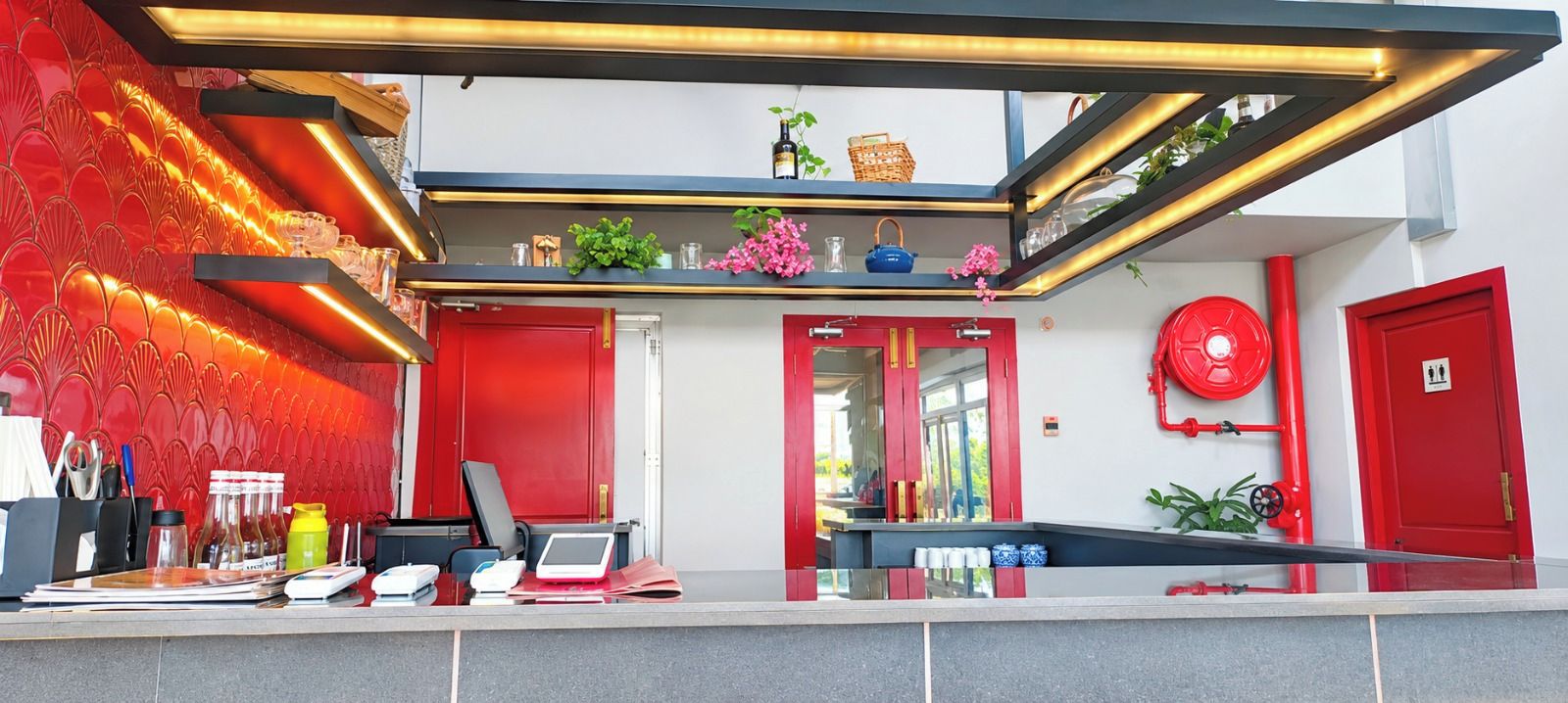 Un moderno vestíbulo de hotel con una decoración roja y blanca, una recepción y una escalera que sube a los pisos superiores.