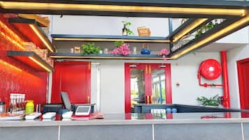 A modern hotel lobby with a red and white color scheme, a reception desk, and a staircase leading to upper floors.