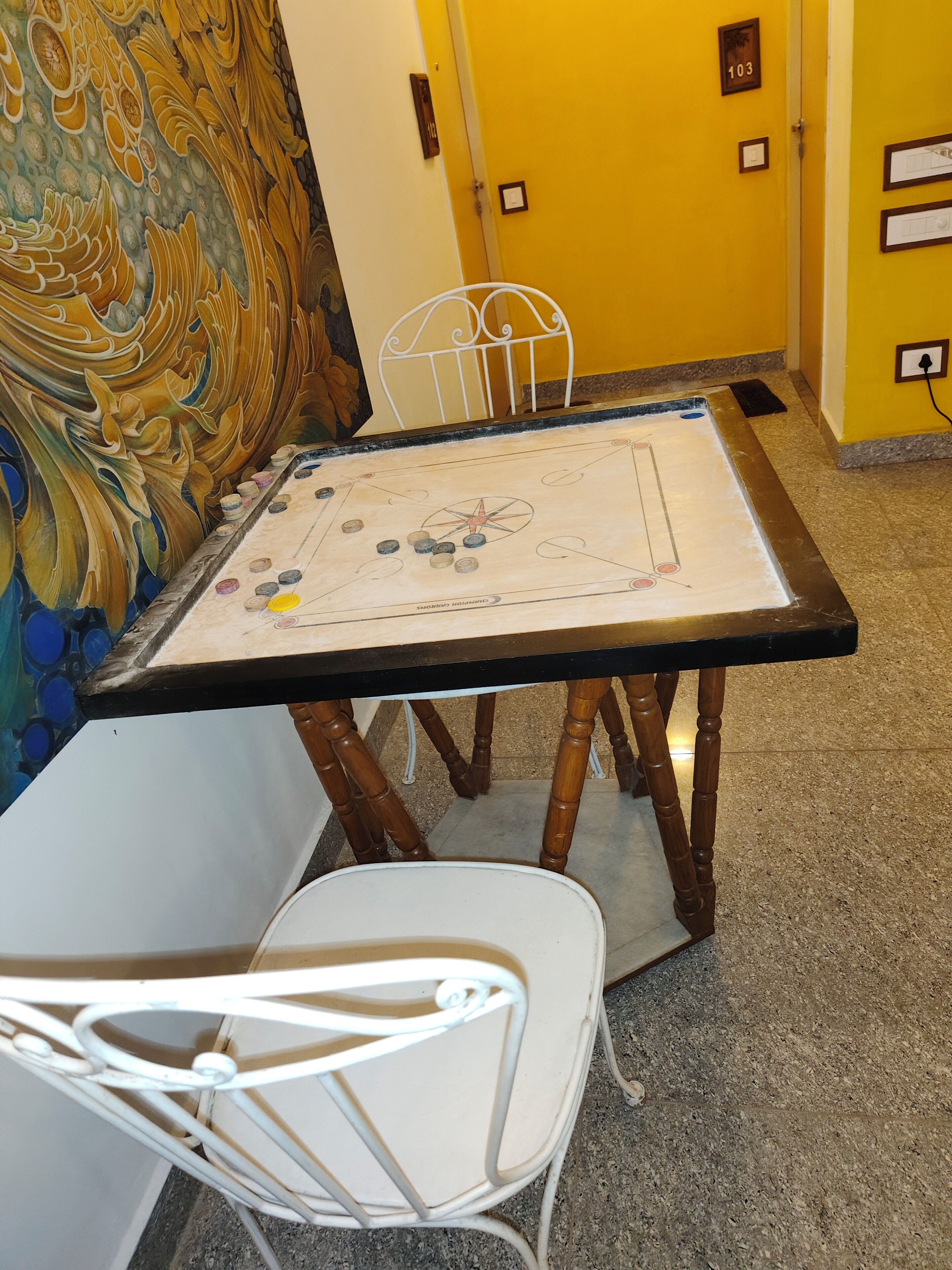 A room with a table set for a game, a chair, and a decorative wall.