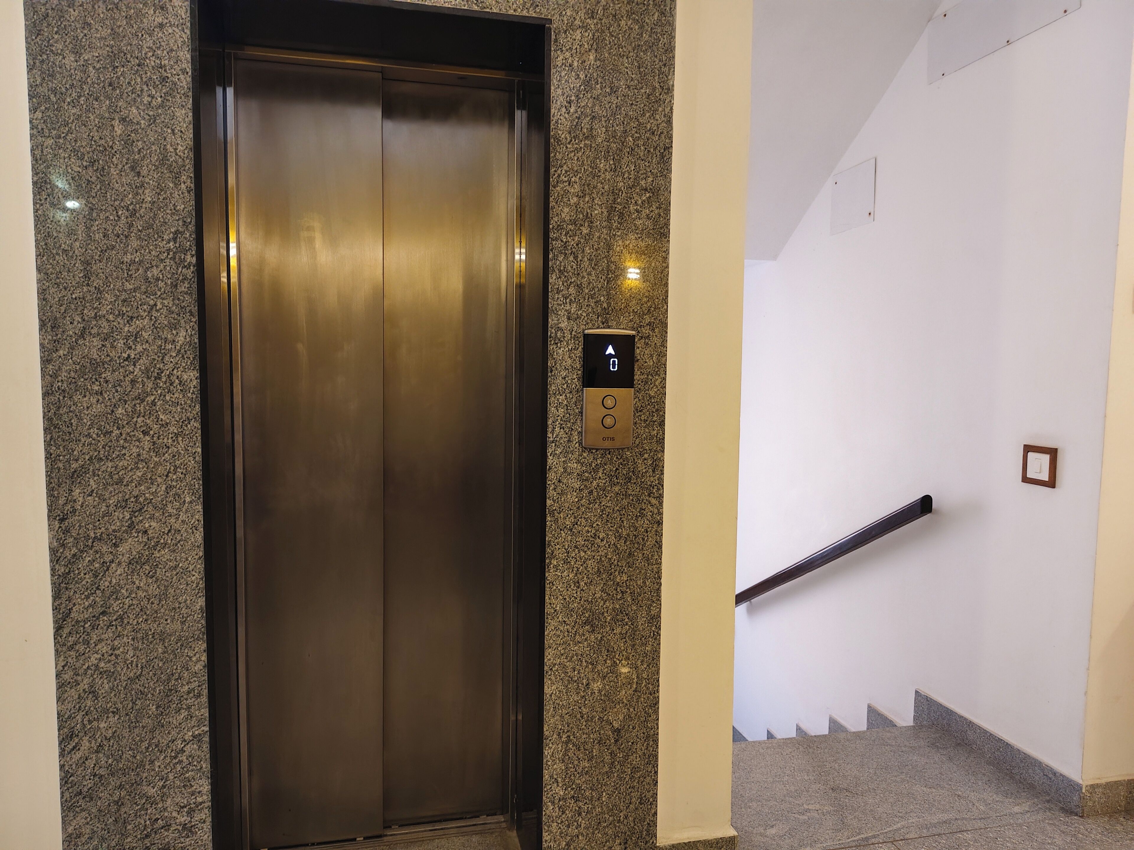 Un ascenseur doté d’un panneau de commande et un escalier muni d’une rampe.
