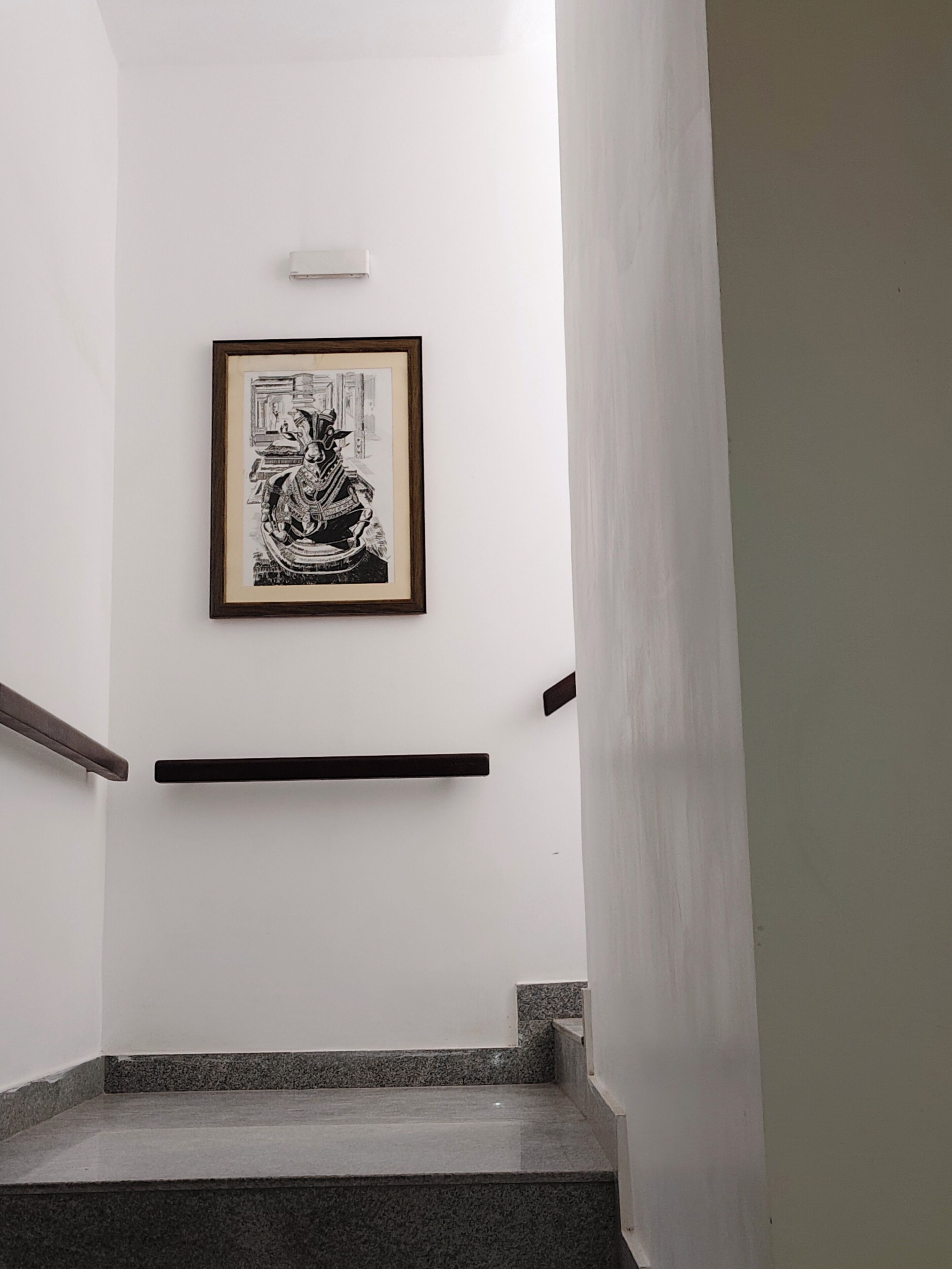 A staircase with a framed black and white artwork on the wall.