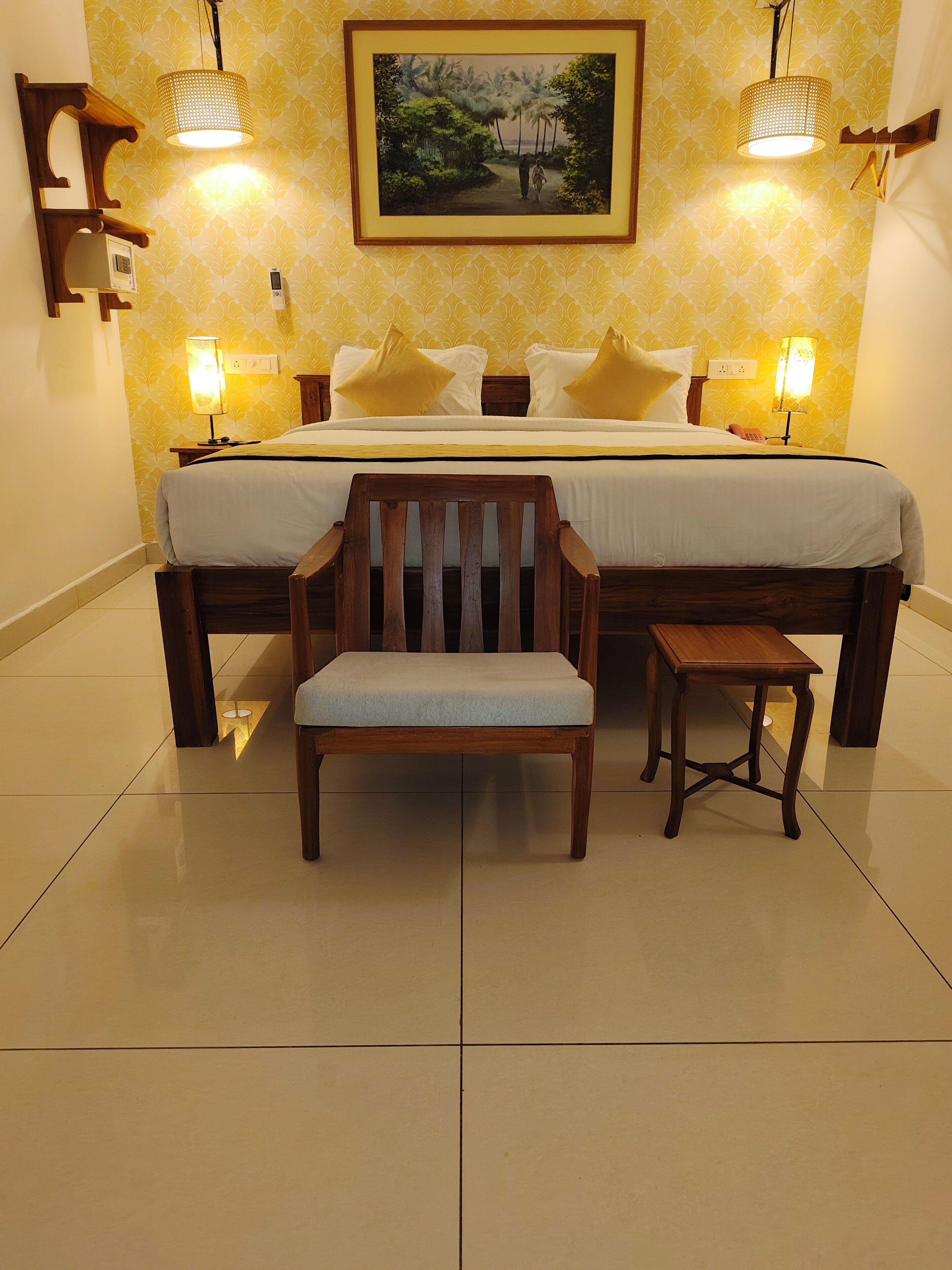 A hotel room with a large bed, two bedside tables, a wooden chair, and a small table.