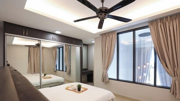 Una habitación de hotel moderna con una cama grande, ventilador de techo, un ventanal con cortinas y un espejo.