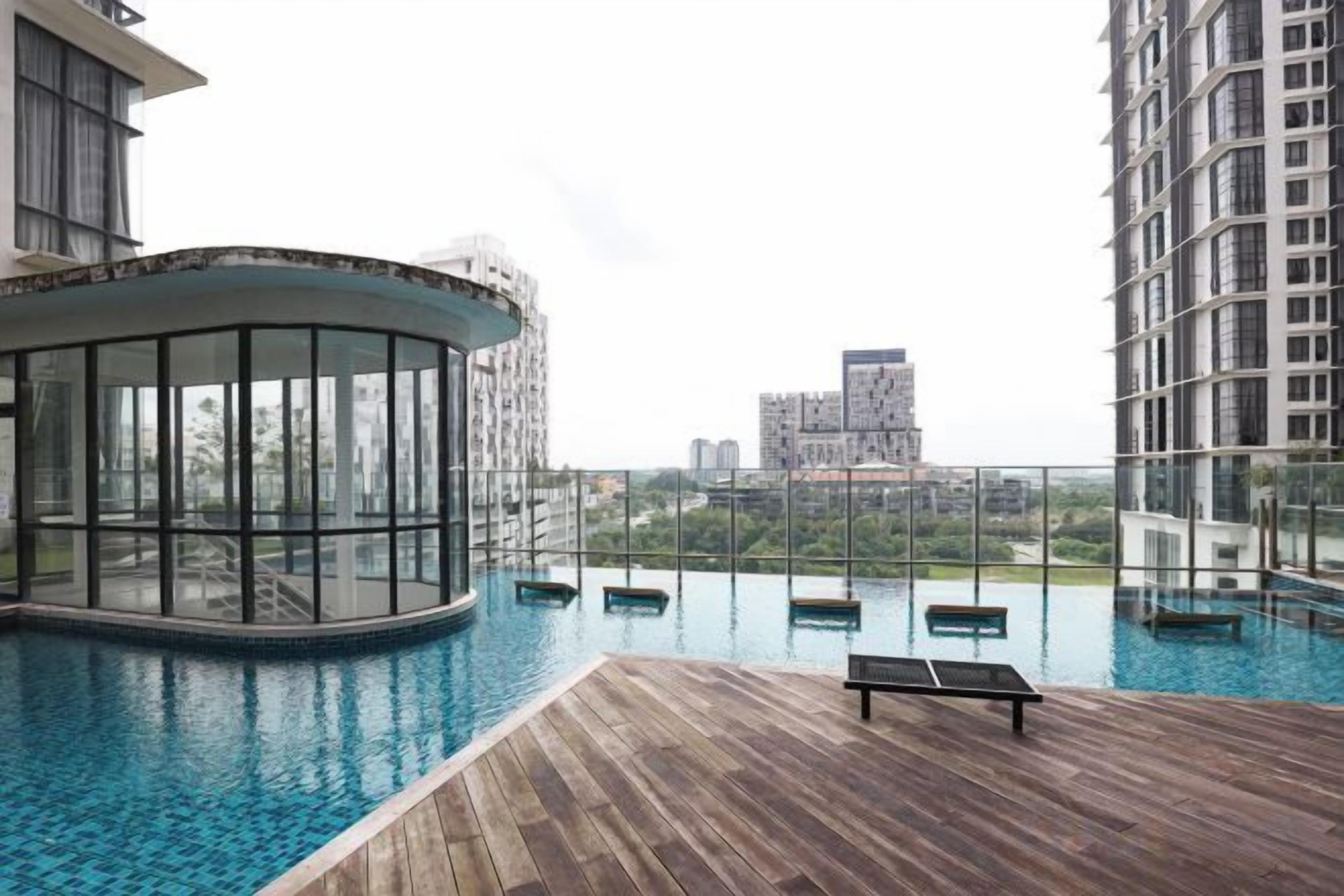 Une piscine à débordement située sur le toit, avec une terrasse en bois, un salon fermé par des baies vitrées et une vue sur les bâtiments environnants.