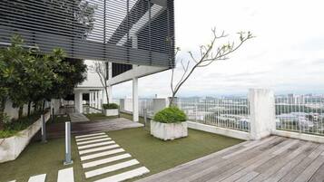 Una terrassa al terrat amb un pont de fusta, una zona de jardí amb plantes i una vista a la ciutat.