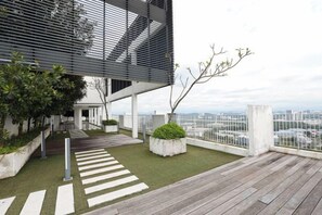 Une terrasse sur le toit avec une plateforme en bois, un petit espace jardin agrémenté de plantes et une vue sur le paysage urbain.