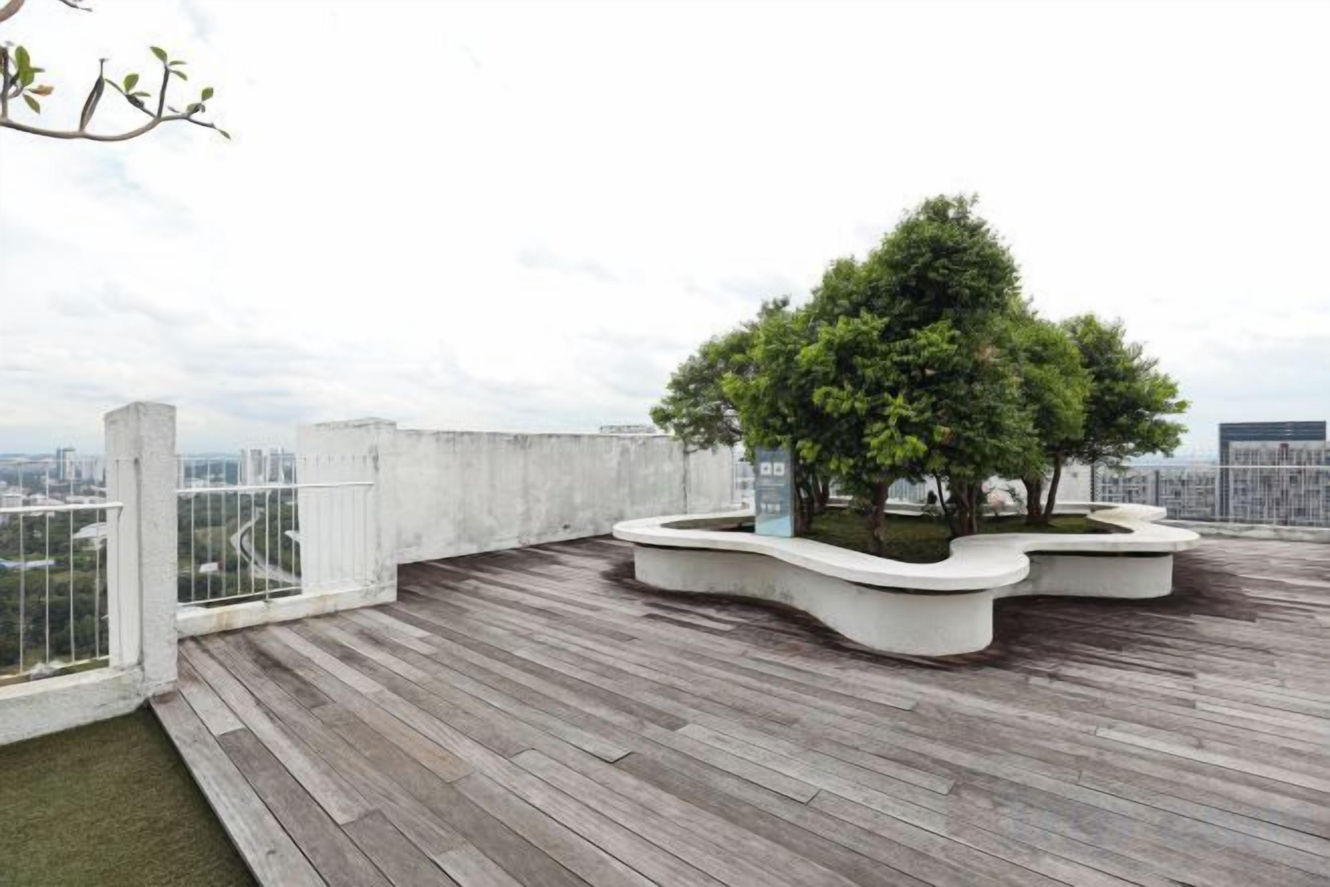 A rooftop terrace with a wooden deck, a tree planter with a tree, and a cityscape view.