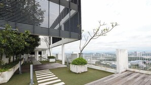 Una terraza en la azotea con cubierta de madera, un camino blanco y vistas de la ciudad.