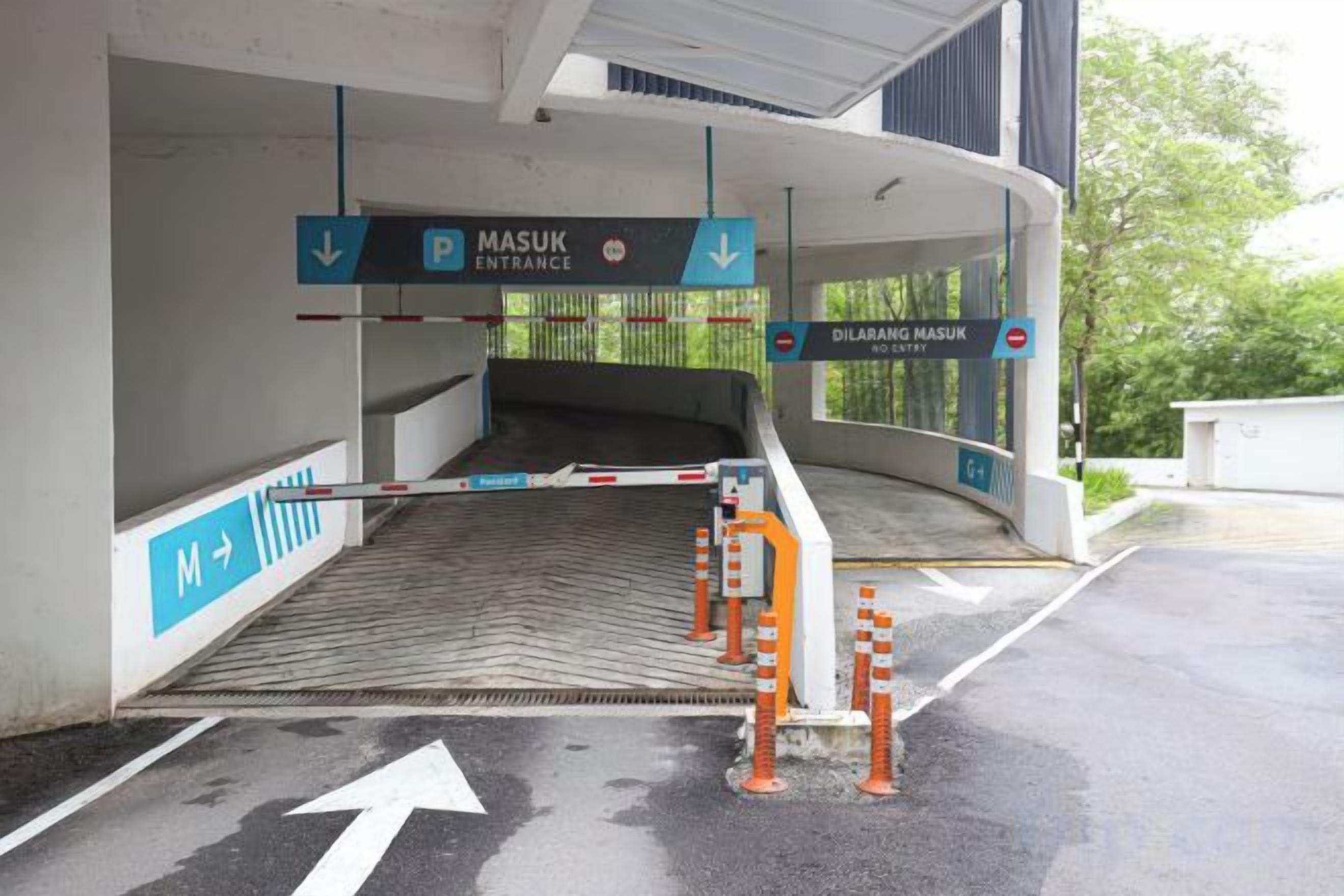 Una entrada vigilada a un estacionamiento con señales direccionales y una barrera.