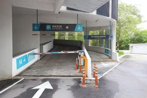 A gated entrance to a parking area with directional signs and a barrier gate. - Solstice Luxury Duplex Cyberjaya By EC (Cyberjaya)