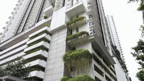 Un moderno edificio de gran altura con varios balcones, algunos con vegetación.