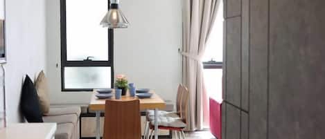 A compact living space with a dining area, a kitchenette, and a large window.