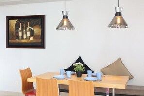 Een eetgedeelte met een houten tafel, blauwe borden en een potplant.