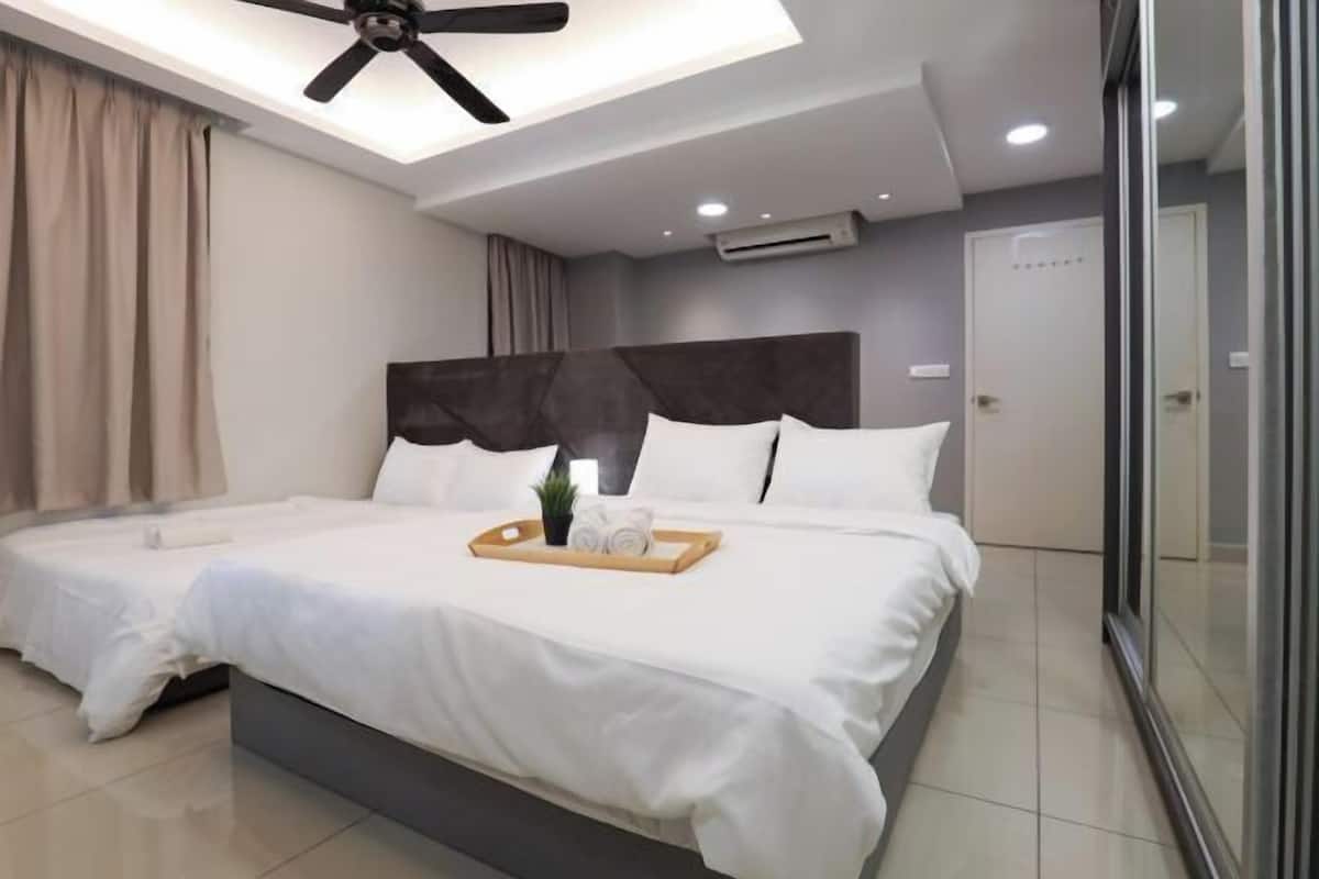 A modern hotel room with a large bed, a ceiling fan, and a bedside table with a tray of towels.