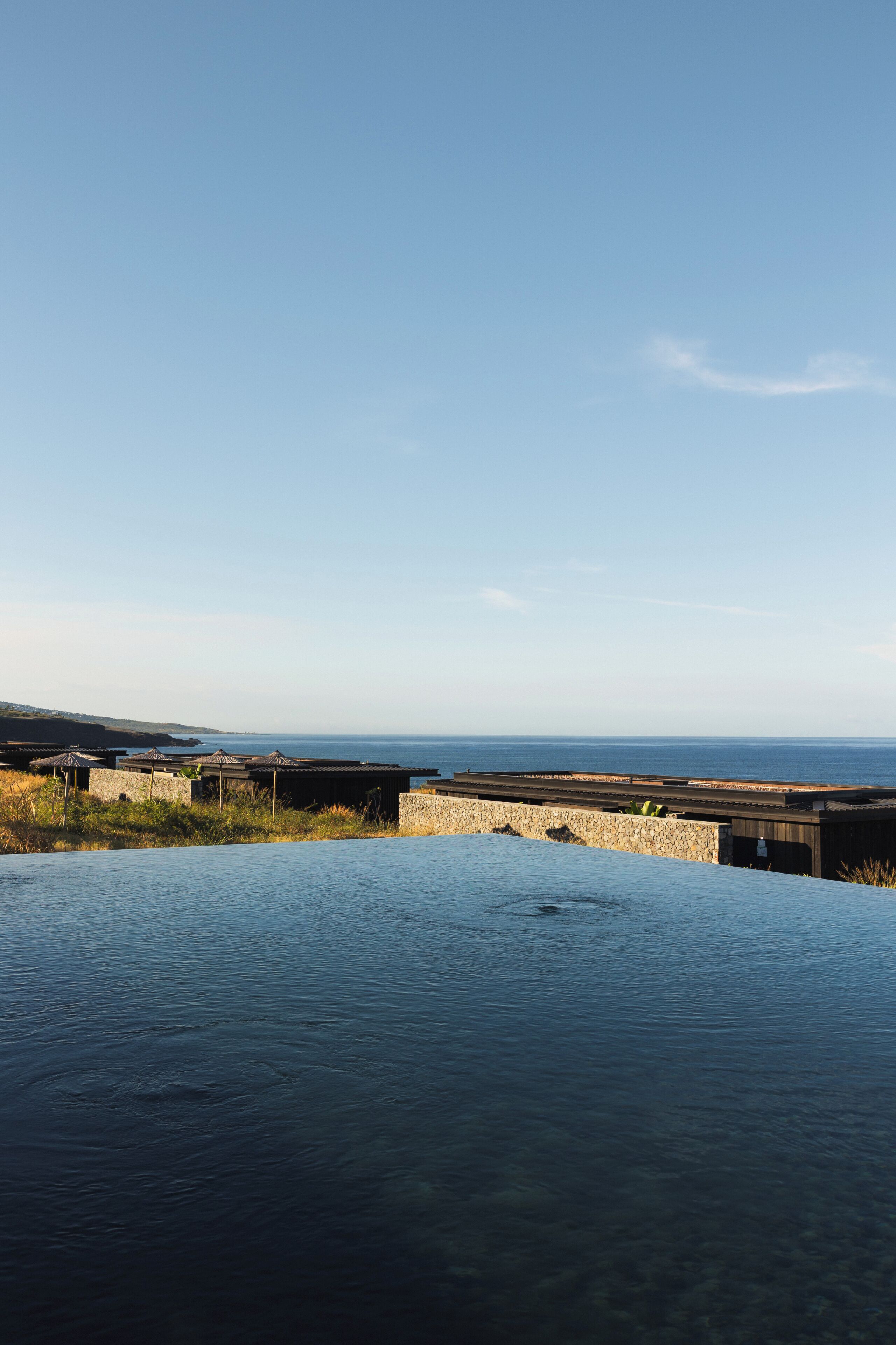A clear view of the sea, a stone wall, and a wooden structure.