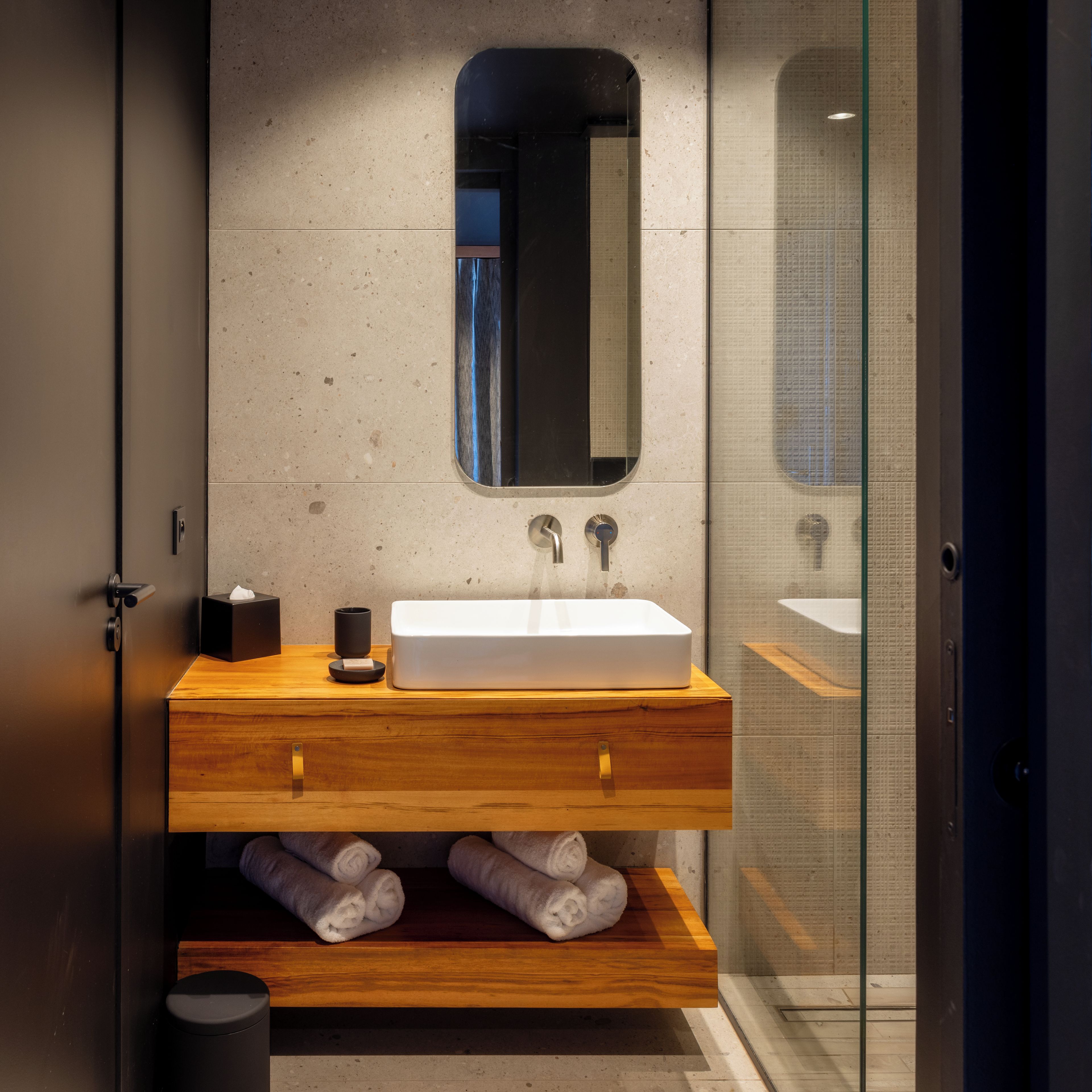 A modern bathroom with a rectangular sink, a mirror, and a wooden vanity.