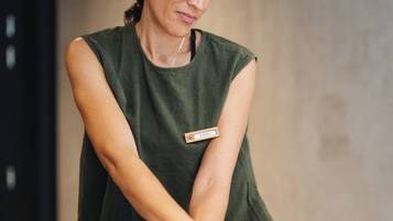 A person receiving a massage in a room with a neutral-colored wall and a gray blanket on the bed.