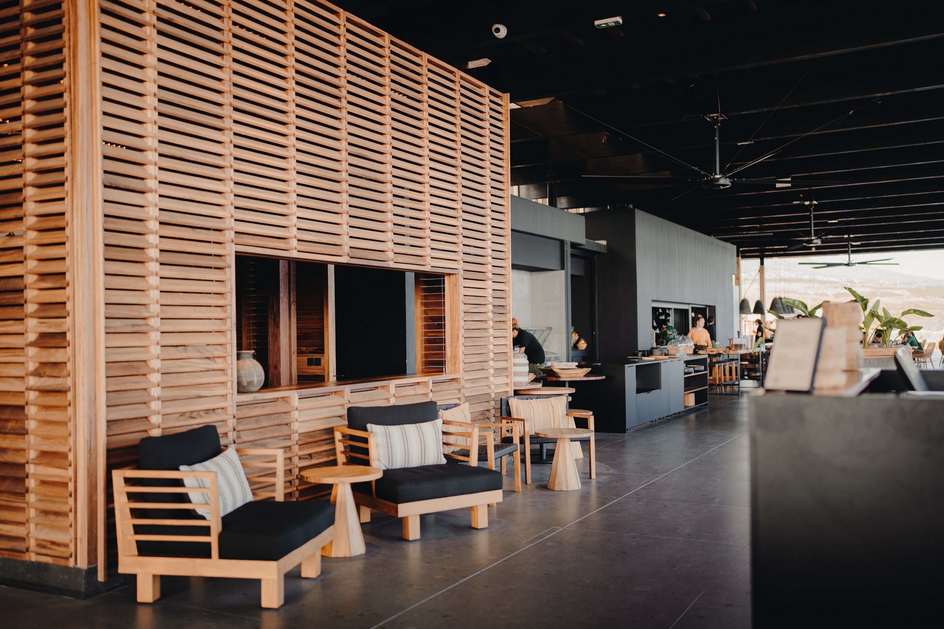 A modern interior with wooden slatted walls, a bar area, and seating arrangements.