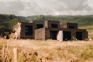 Um edifício moderno com telhado plano, grandes janelas e base de pedra.