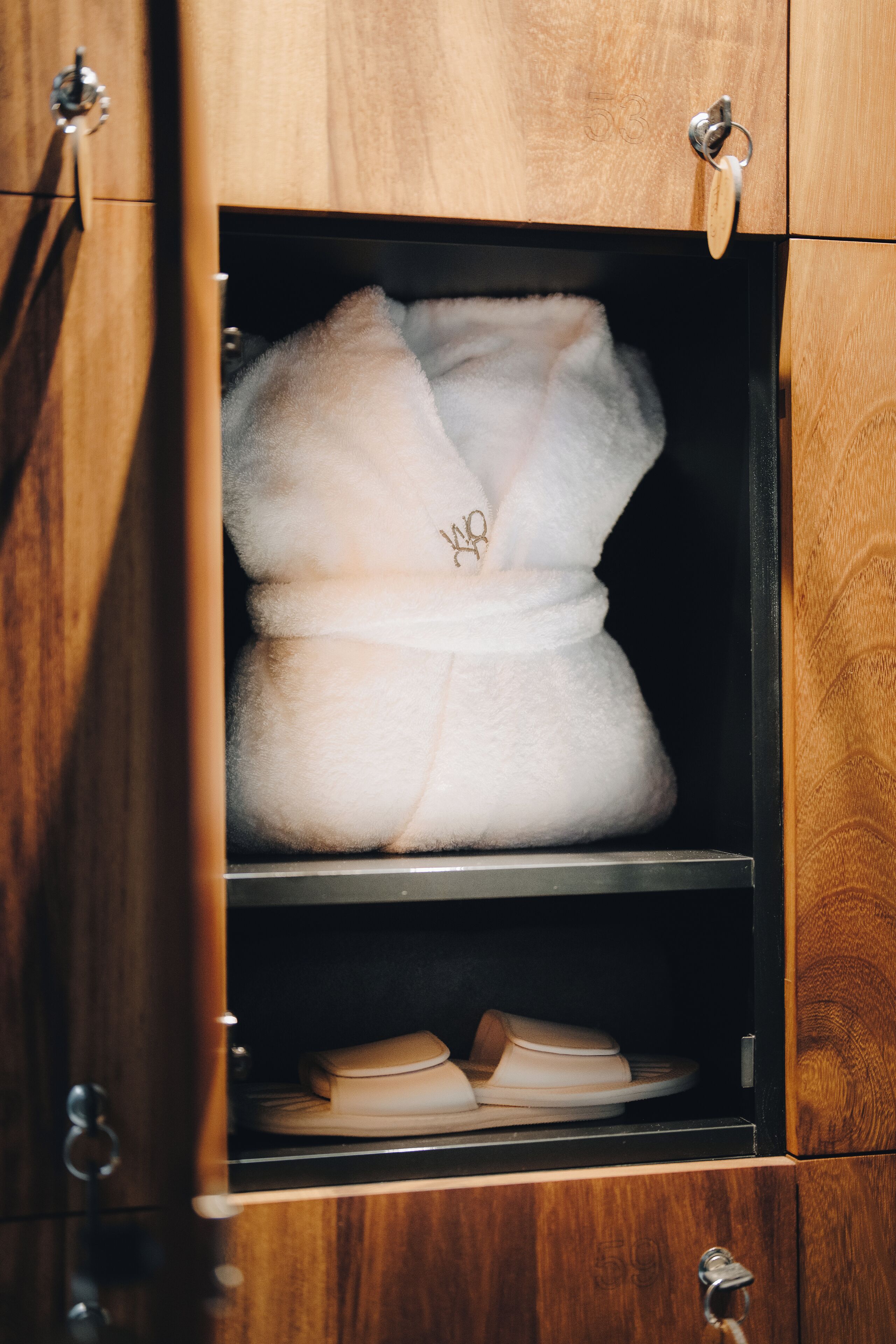 A wooden wardrobe with a white robe hanging inside.