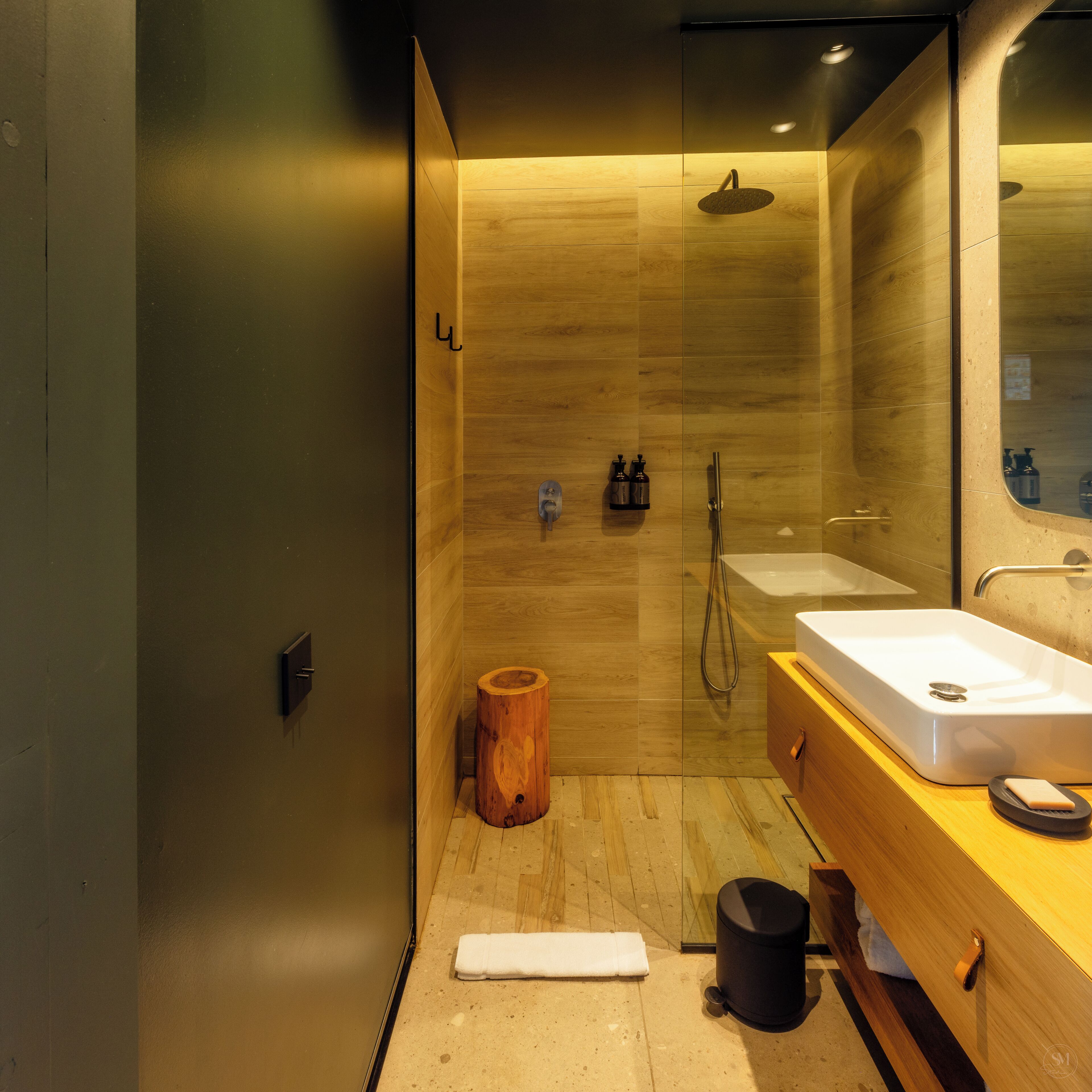 Une salle de bain moderne avec un meuble-lavabo en bois, un grand miroir, une douche et des toilettes.