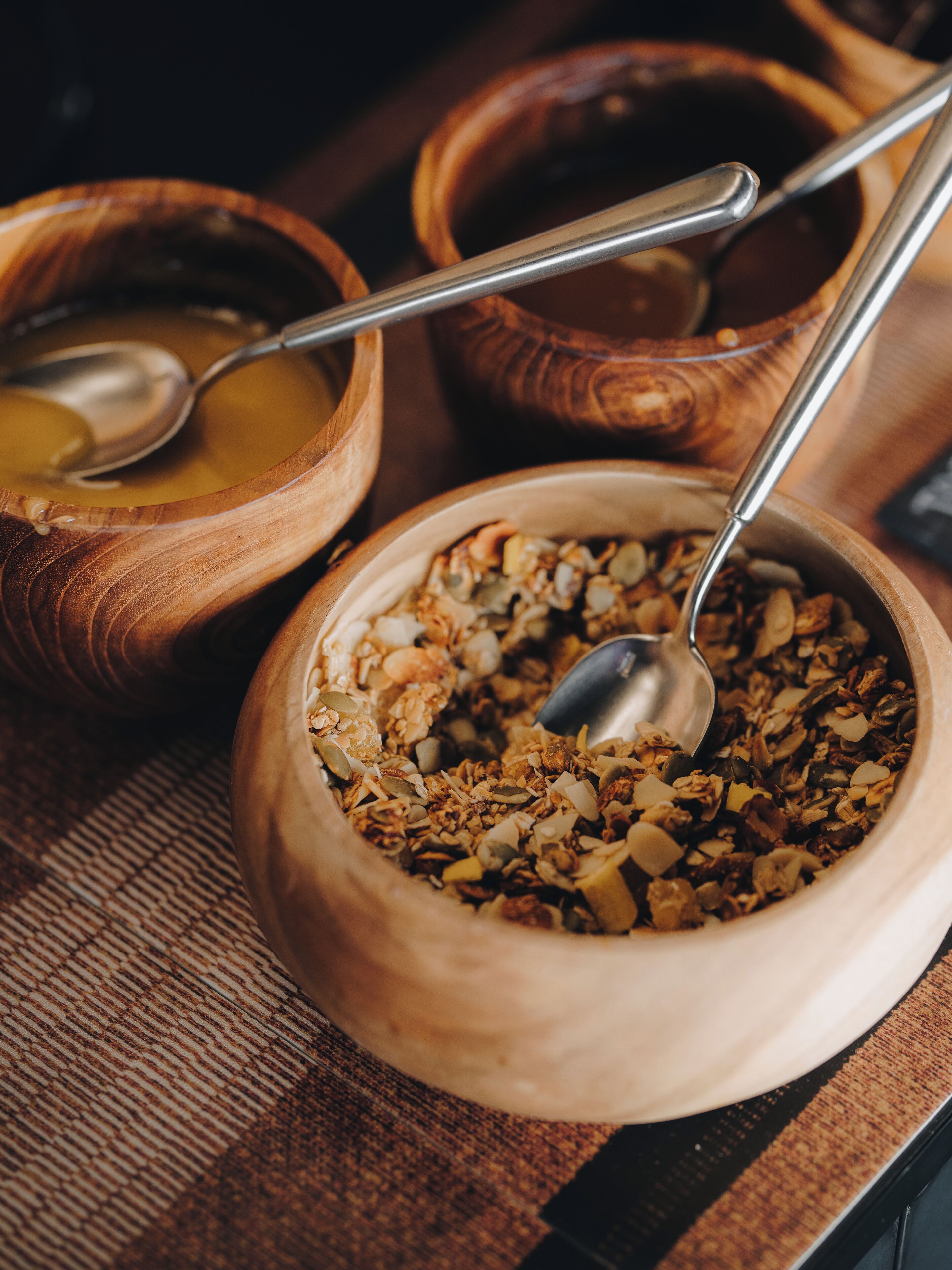 A wooden bowl filled with granola and a spoon inside it.