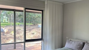 A bedroom with a large bed, a sliding glass door leading to an outdoor area, and a ceiling light fixture.
