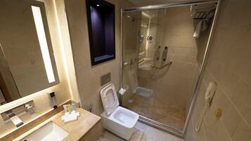Un baño moderno con ducha acristalada, inodoro blanco y un espejo grande.