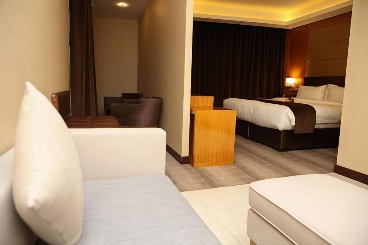 A hotel room with a bed, a sofa, a small table, and a chair.