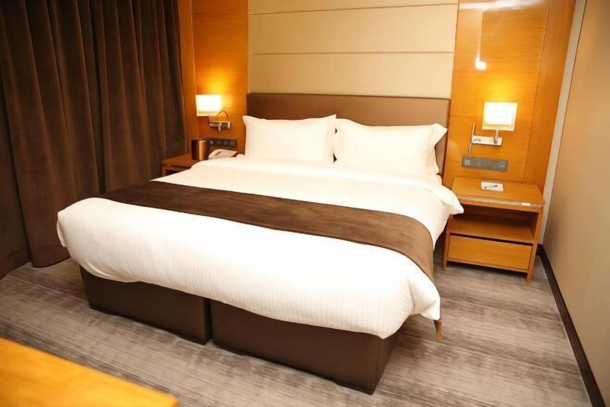 A hotel room with a large bed, two bedside tables, and a nightstand.