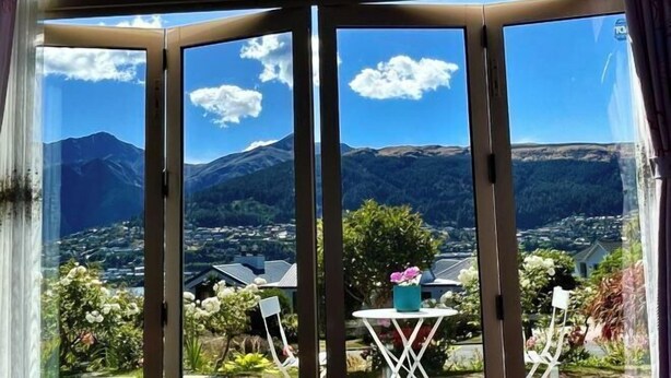 Una stanza con un'ampia finestra che si affaccia su montagne e una città sottostante.