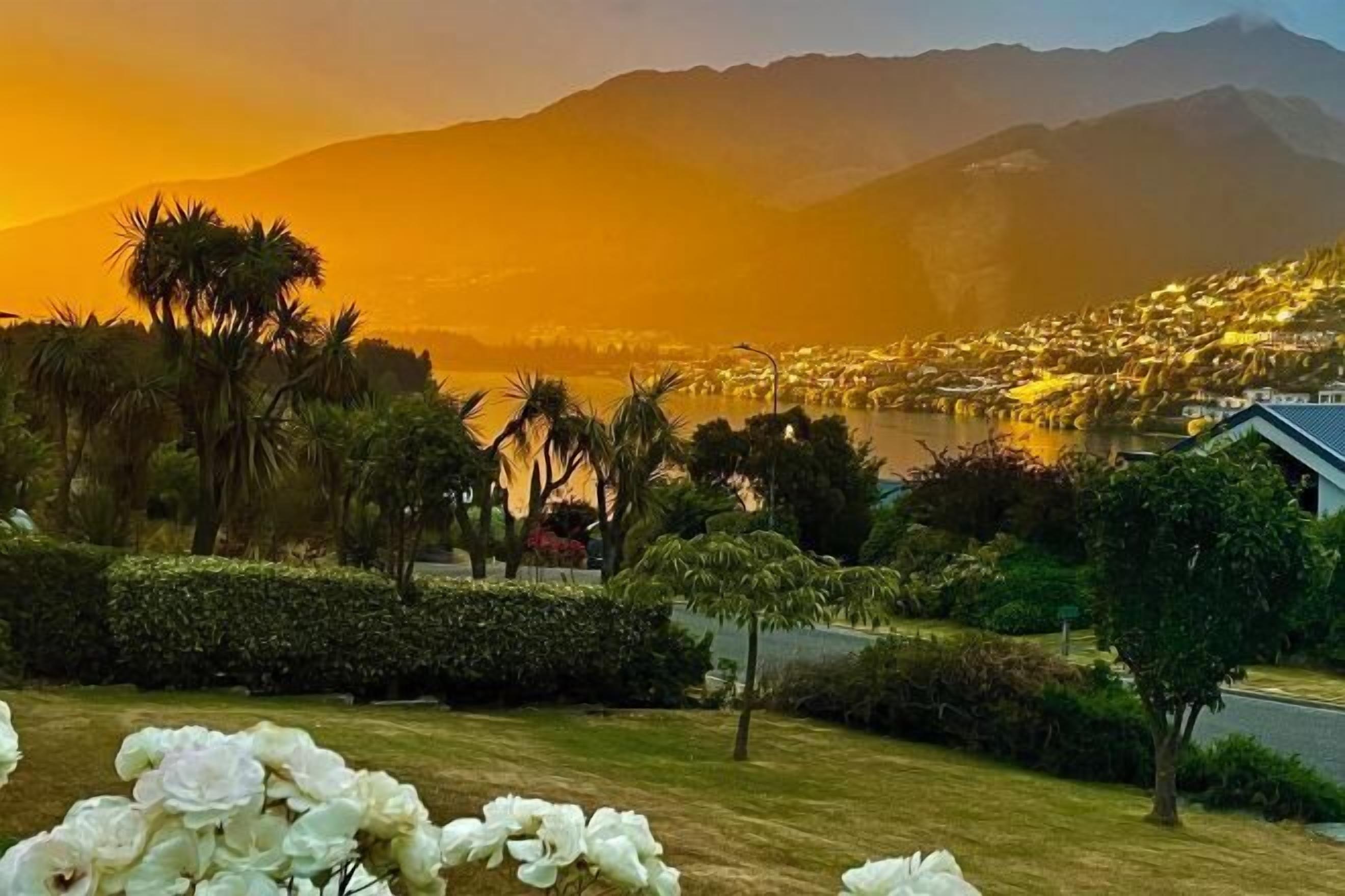 A coastal town with a mountain backdrop, lush greenery, and a body of water.