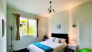 Camera da letto con letto, comodino, lampada, armadio e finestra con tende.