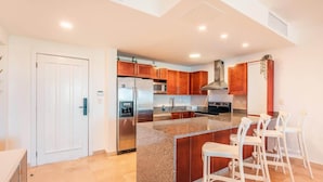 A modern kitchen with a central island, stainless steel appliances, and wooden cabinets. - Ocean View Apartment w/ Pool in Cap Cana (Punta Cana)