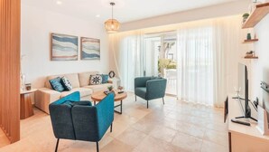 A modern living room with a sofa, two armchairs, a coffee table, and a TV. - Ocean View Apartment w/ Pool in Cap Cana (Punta Cana)