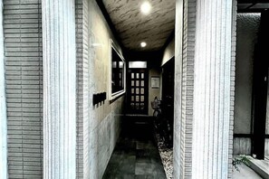 A narrow hallway with a tiled floor, a door at the end, and a window on the left. - MIZUNOMICH IRYOKAN (Osaka)