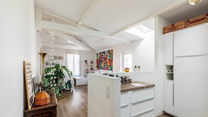 Une cuisine lumineuse avec des meubles blancs, un plan de travail en bois et une lucarne.