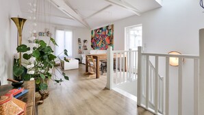 Un vaste espace de vie doté d’un haut plafond, d’une table à manger et d’un escalier menant à un niveau supérieur.