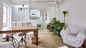 Un vaste espace de vie comprenant une table à manger en bois, des fauteuils blancs et un canapé blanc.