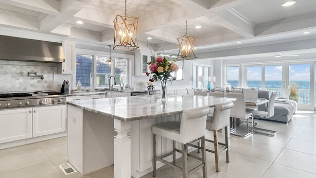 A spacious kitchen with a large island, white cabinetry, and a view of the ocean.