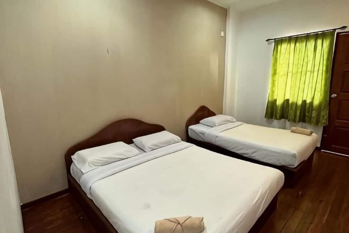 Ein Zimmer mit zwei Betten, Holzboden und einem grünen Vorhang.