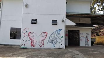 A building facade with a mural of wings and stars, a door with a sign, and a small figure.